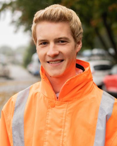 Mann in orangefarbener Arbeitsjacke lächelt
