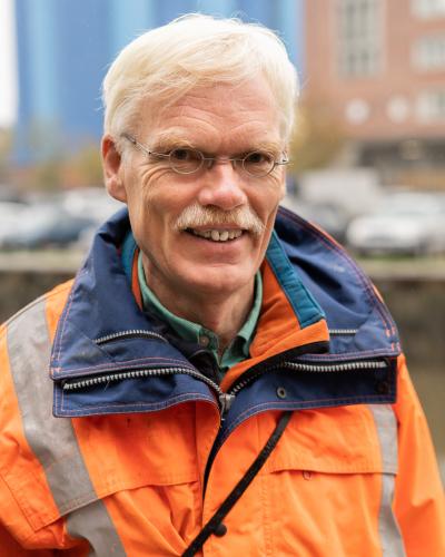 Mann in orangefarbener Arbeitsjacke lächelt
