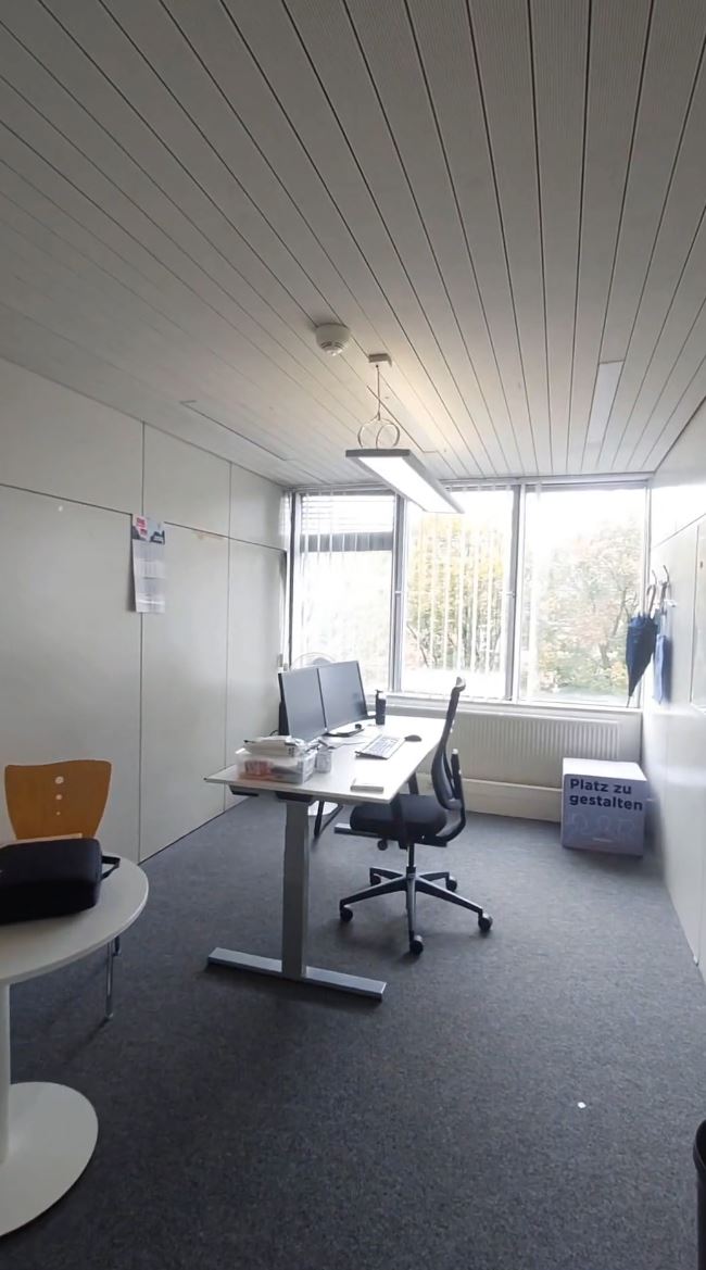 Ein Blick in ein Büro im Rathaus. Man sieht links vorn ein Stück grauen Besprechungstisch und in der weiteren Flucht des Bildes den Schreibtisch mit Bildschirmen und Tastatur. Das Büro ist hell, die Sonne scheint durch das Fenster.